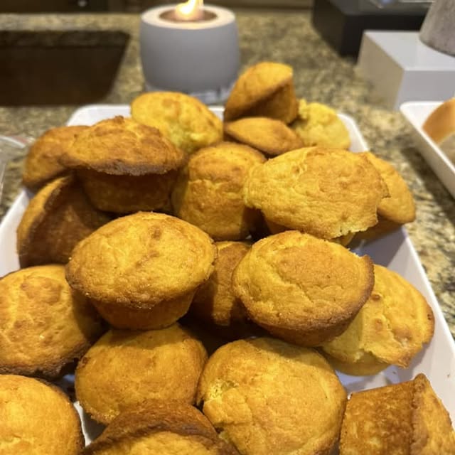 A box filled with golden cornbread muffins